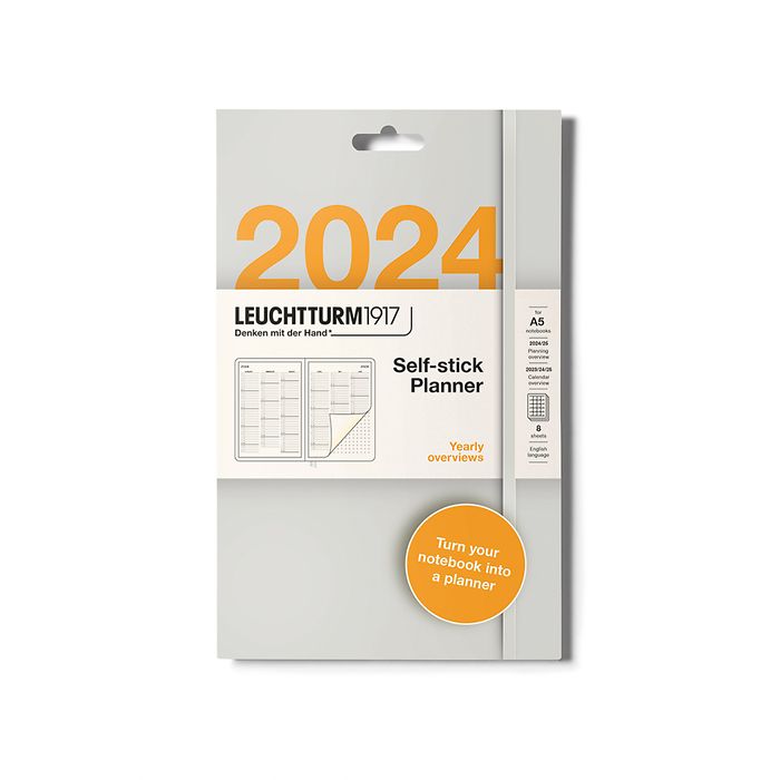 Retail packaging in grey and white for self-stick planner stickers by brand Leuchtturm1917. It shows the year grid over two A5 pages in a small illustration and that it's for the year 2024. It also has an orange circle towards the bottom and in white writing it says 'turn your ntoebook into a planner'.