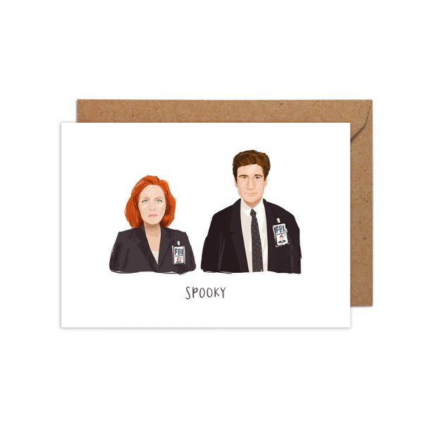 A greetings card with a white background and a colour illustration of two characters - Mulder and Scully from the 1990s TV show X Files with the phrase below in handwritten capital letters &#39;spooky&#39;.
