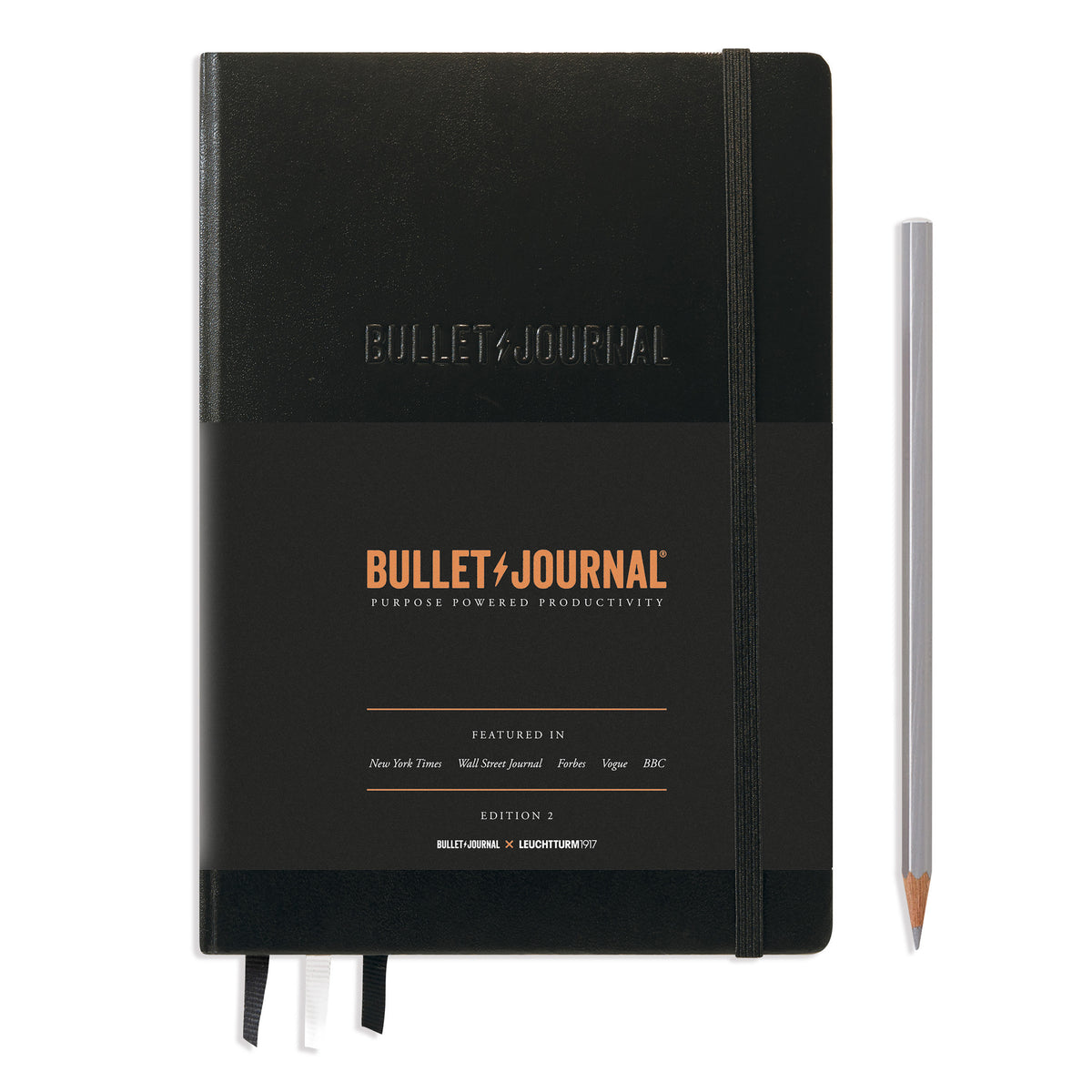A black bullet journal notebook. It has an elastic band keeping it together and a black paper band covering three quarters of the book detailing that it&#39;s a bullet journal. Embossed on the front cover are the words in capitals BULLET JOURNAL.