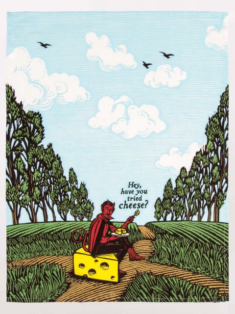 A tea towel featuring the design of a red devil in a field sitting on a wedge of cheese, offering you a wedge of cheese by asking &#39;hey, have you tried cheese?&#39;