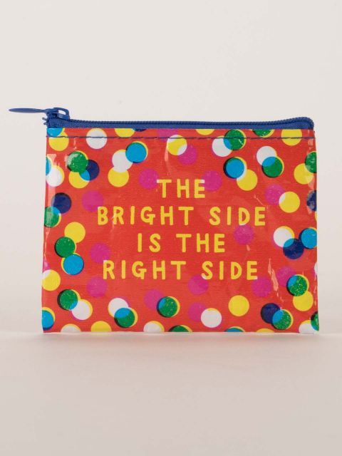 An orange coin purse with the words 'the bright side is the right side' on one side. The spots are a mix of white, green and blue, the zip is royal blue and the writing is in capitals in yellow.