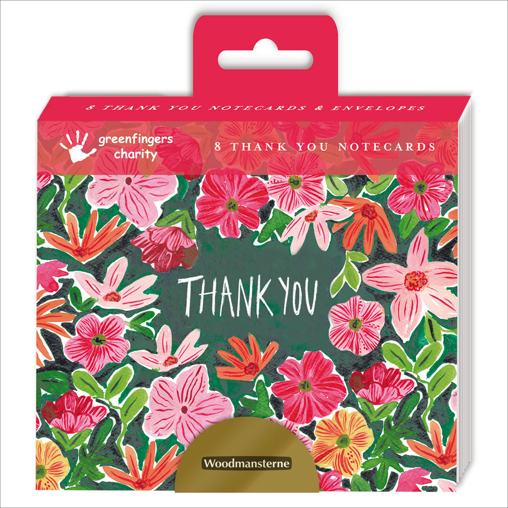 An image of a pack of 8 notecards by Woodmansterne Publishing. It shows a preview on the card design which has the words THANK YOU in white surrounded by pink, red and orange flowers.