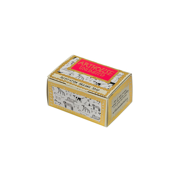 A cuboid shape box with guilded gold edging and a bright red/pink label stating the company Arthouse Unlimited. There is a background illustration of black outlined dogs. The box also states the words 'meditation organic soap'.