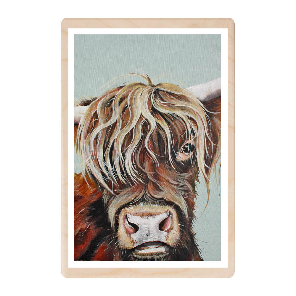 This wooden postcard features a painted head of a Highland Cow. The cows eye is peeking cheekily through it's long hair.