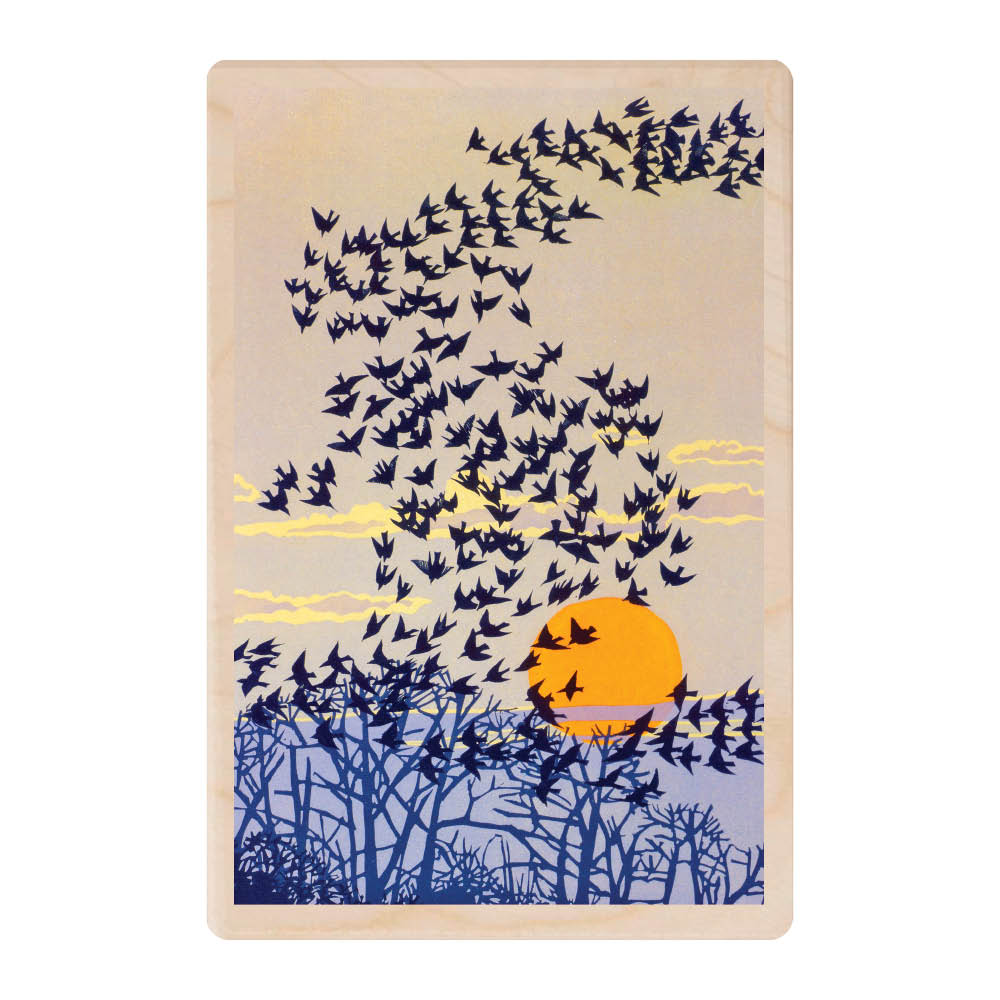A wooden postcard featuring a beige background with an orange sun setting in the background, shadows of a forest in foreground in blue and across the sky hundreds of dark coloured Starling birds flying in a formation.