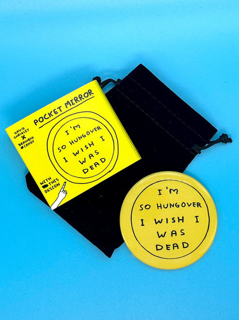 A yellow round pocket mirror with black handwriting saying I'm so hungover I wish I was dead by artist DAvid Shrigley. There is a black velvet drawstring pouch that is comes in and bright yellow packaging to match.