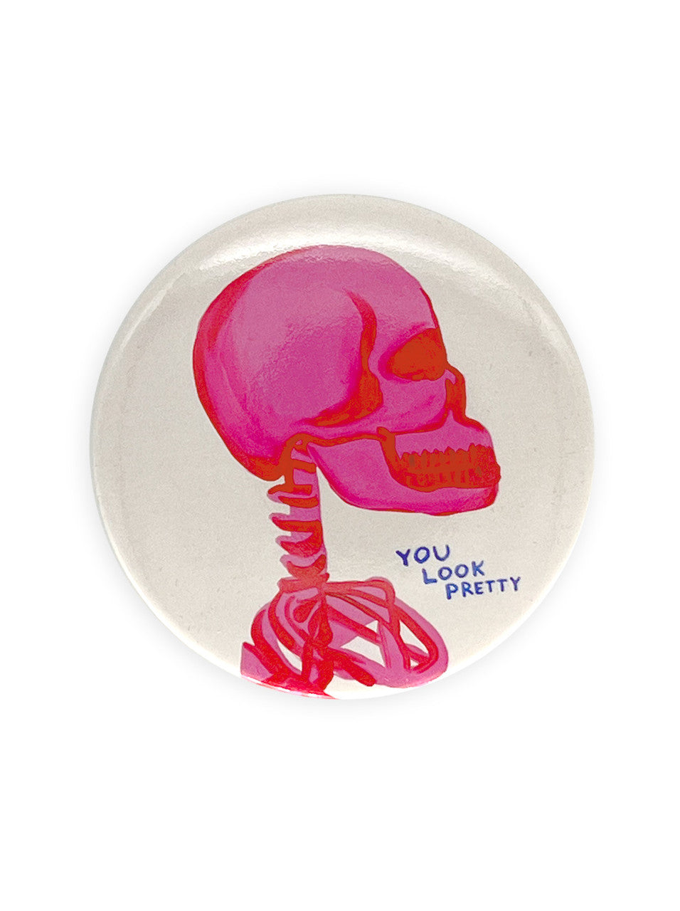 A white round pocket mirror with drawing of a pink skeleton from the shoulders and navy handwriting saying You Look Pretty by artist DAvid Shrigley. 