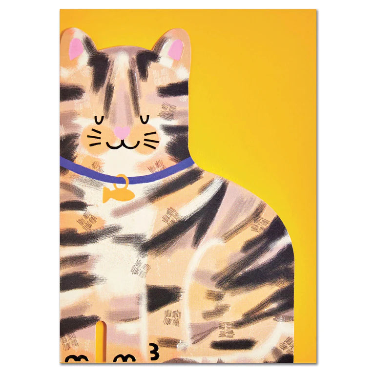 A card cut out in the shape of a brown and black striped tabby cat with it&#39;s eyes closed. The cat is sitting happily and has a fish shape attached to it&#39;s navy colour. A yellow envelope is behind the cat.