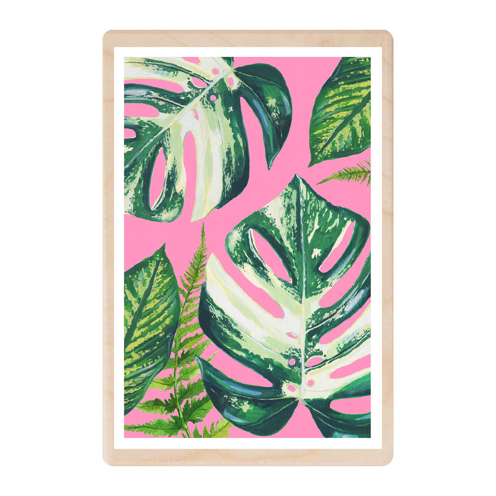 A wooden postcard featuring a bright pink background and giant tropical leaves in different shades of green.