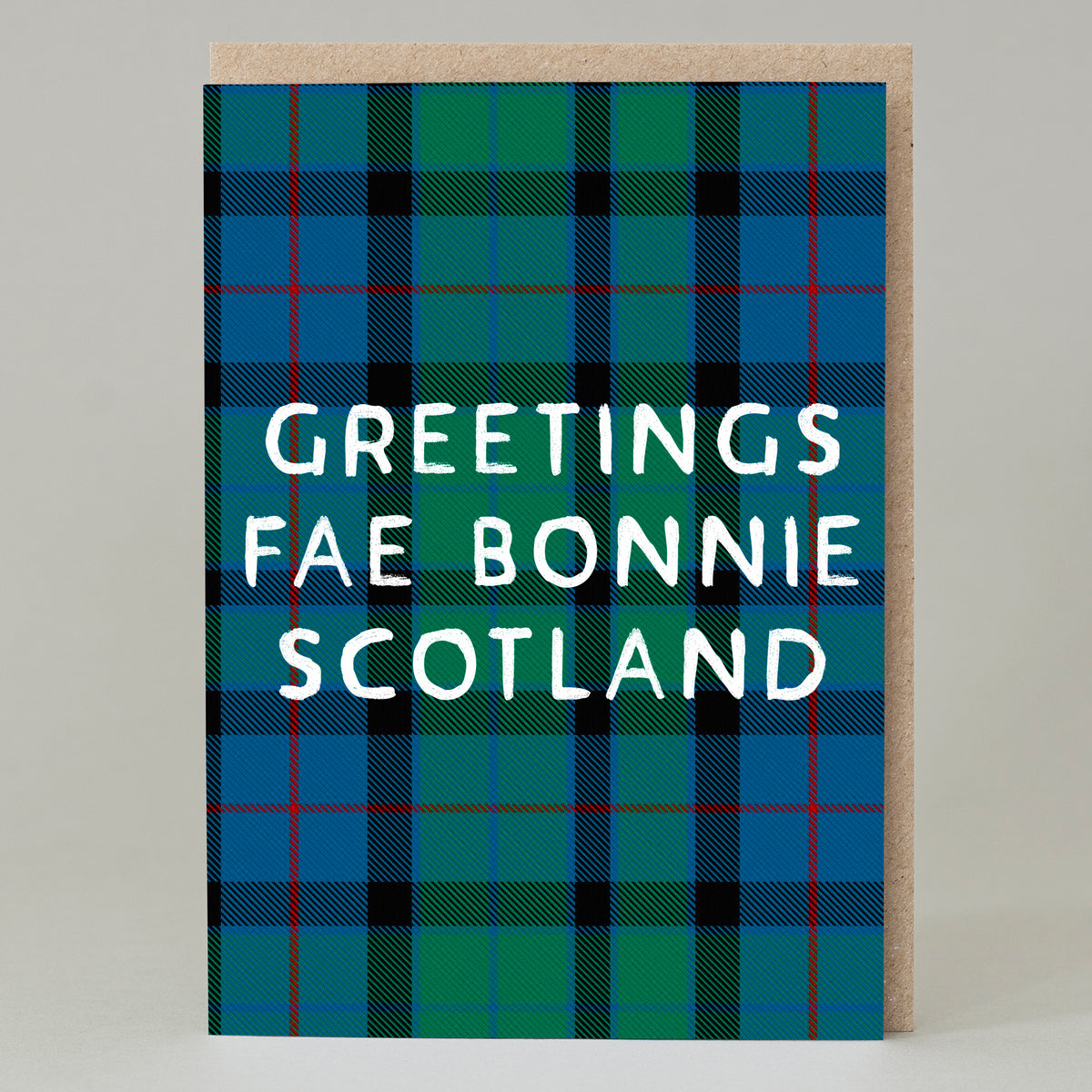 A royal blue and racing green cross hatch tartan patten with thin red accents saying the words greetings fae bonnie scotland in white capital letters