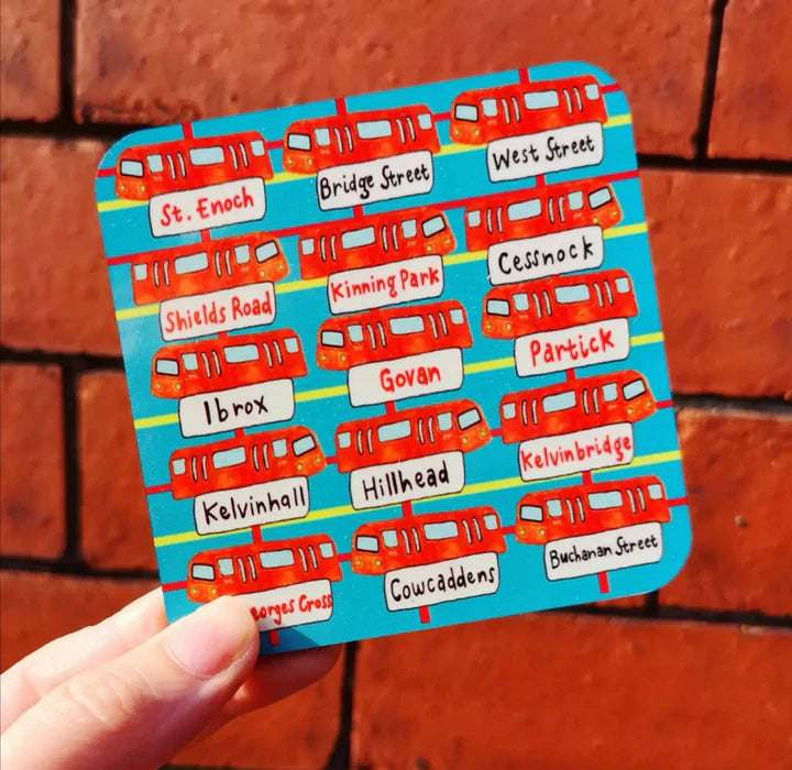 A coaster with a sky blue lightly tartan background and several orange Glasgow subway cars with their station placards denoted underneath.