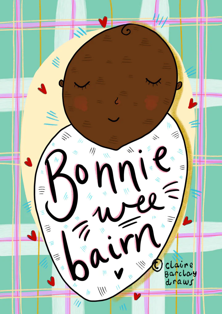 A greetings card with green and pink tartan background and Afro heritage baby swaddled in a white blanket, with wording Bonnie Wee Bairn across it.