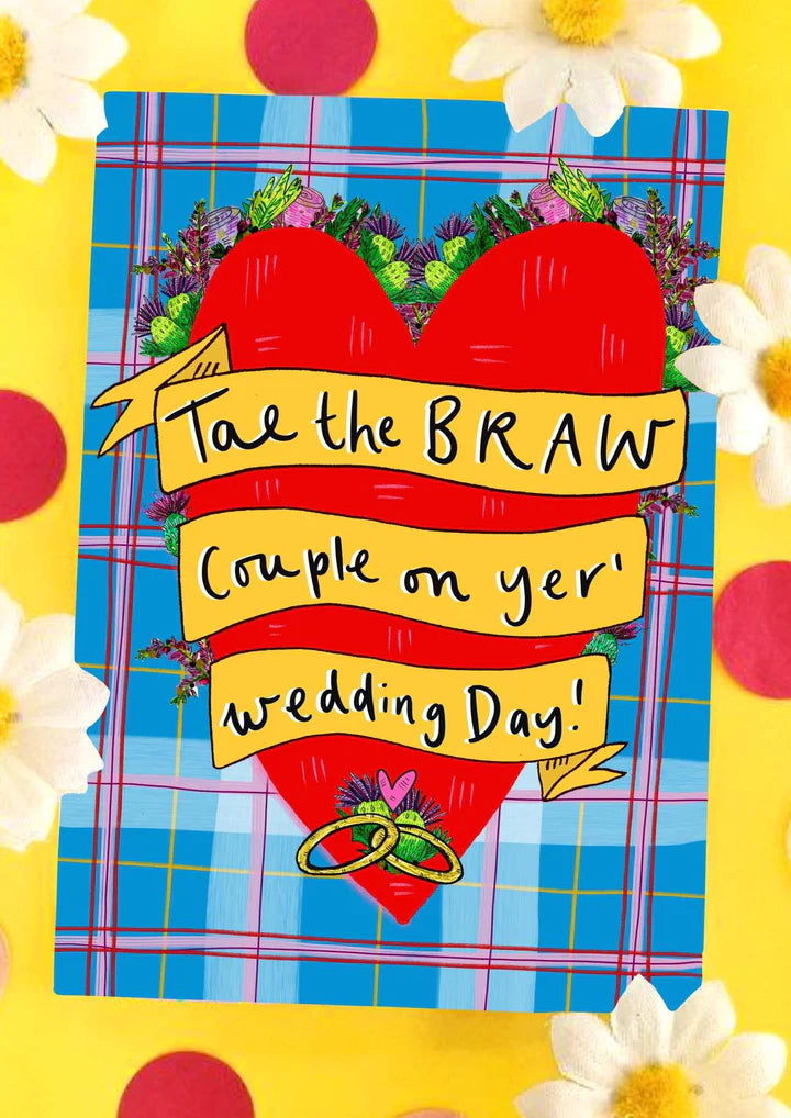 A greetings card with blue, pink and red tartan background, featuring a huge red loveheart with gold rings entangled at the bottom and a yellow banner criss crossing the heart saying the words TAE THE BRAW COUPLE OF YER WEDDING DAY.