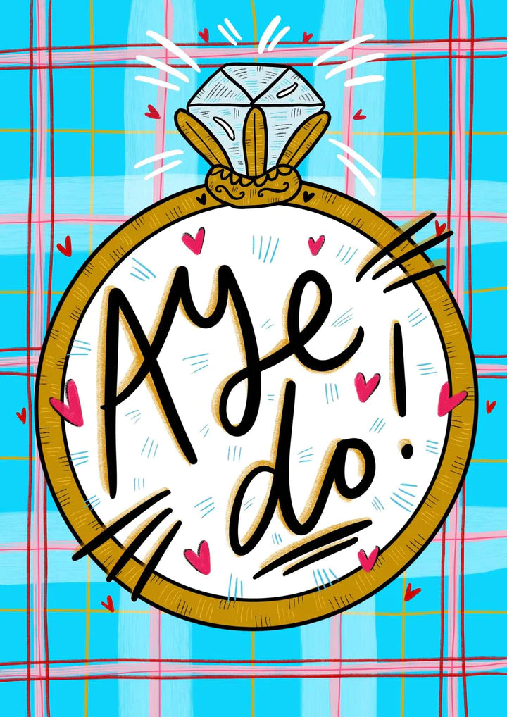 A greetings card with blue, pink and red tartan background, featuring a large diamond ring and the words AYE DO in the middle.